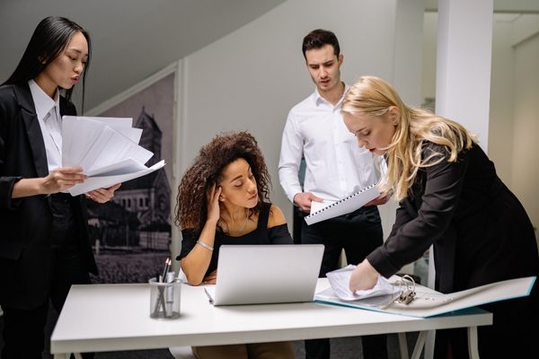 Real estate office staff reviewing compliance paperwork together